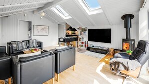 A spacious loft with high ceilings, a skylight, a fireplace, and a cozy seating area with sofas and a coffee table.