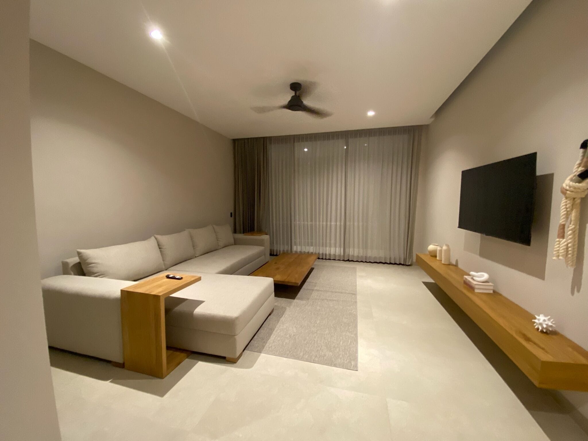 A modern living room with a sofa, coffee table, and a TV mounted on the wall.