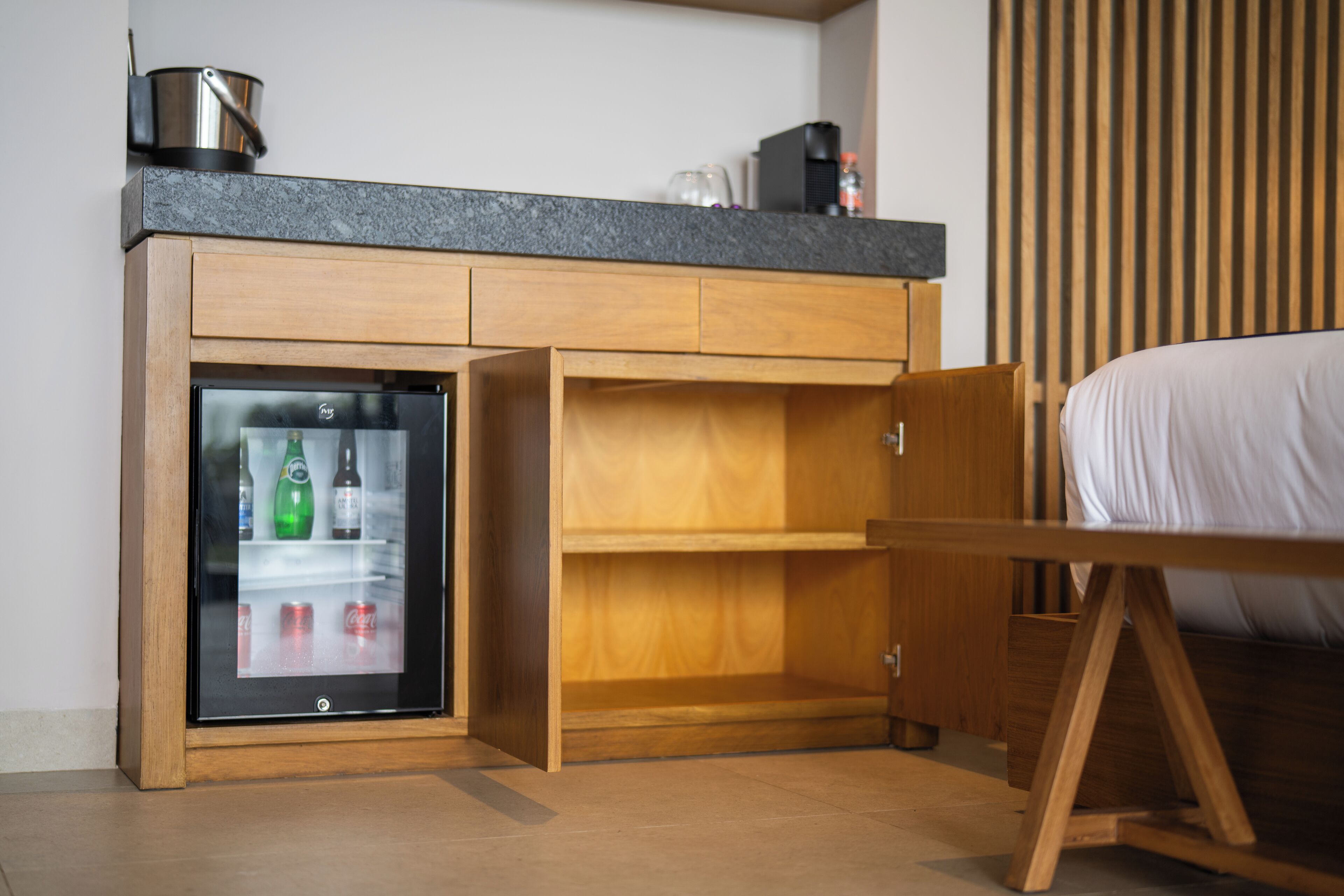 Une chambre compacte équipée d’un mini-réfrigérateur intégré, d’un lit et d’une armoire en bois.