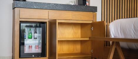 Une chambre compacte équipée d’un mini-réfrigérateur intégré, d’un lit et d’une armoire en bois.