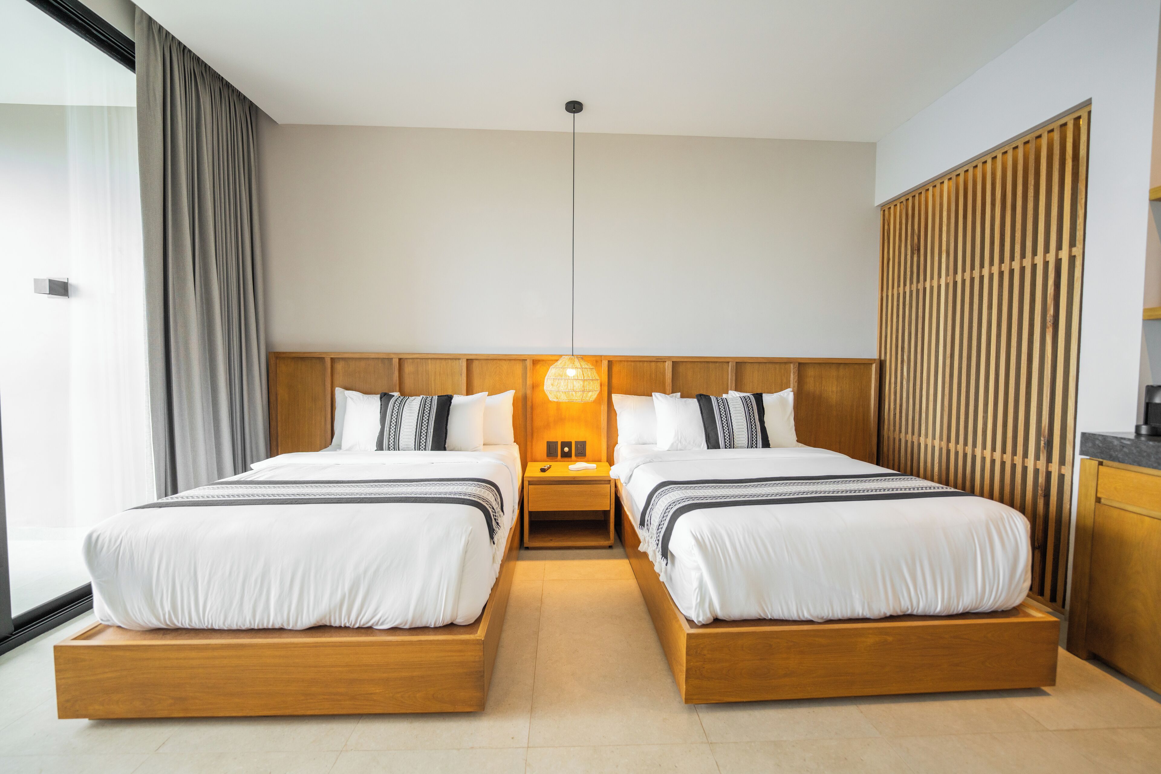 A double bed with a wooden frame, two bedside tables, a wall-mounted lamp, and a sliding wooden door.