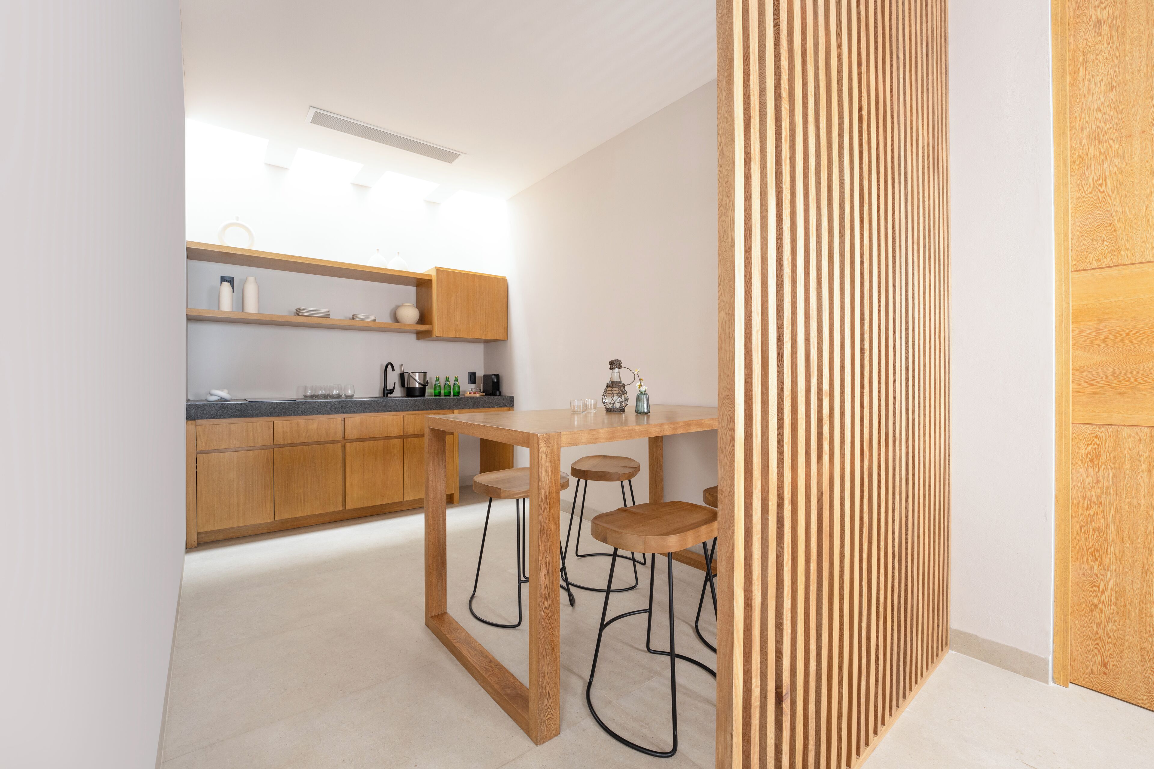 A modern kitchen with wooden cabinets, a countertop, and bar stools.