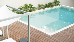 A swimming pool with a wooden deck, white lounge chairs, and a covered seating area. - Amaranto Hotel Boutique (Bacalar)