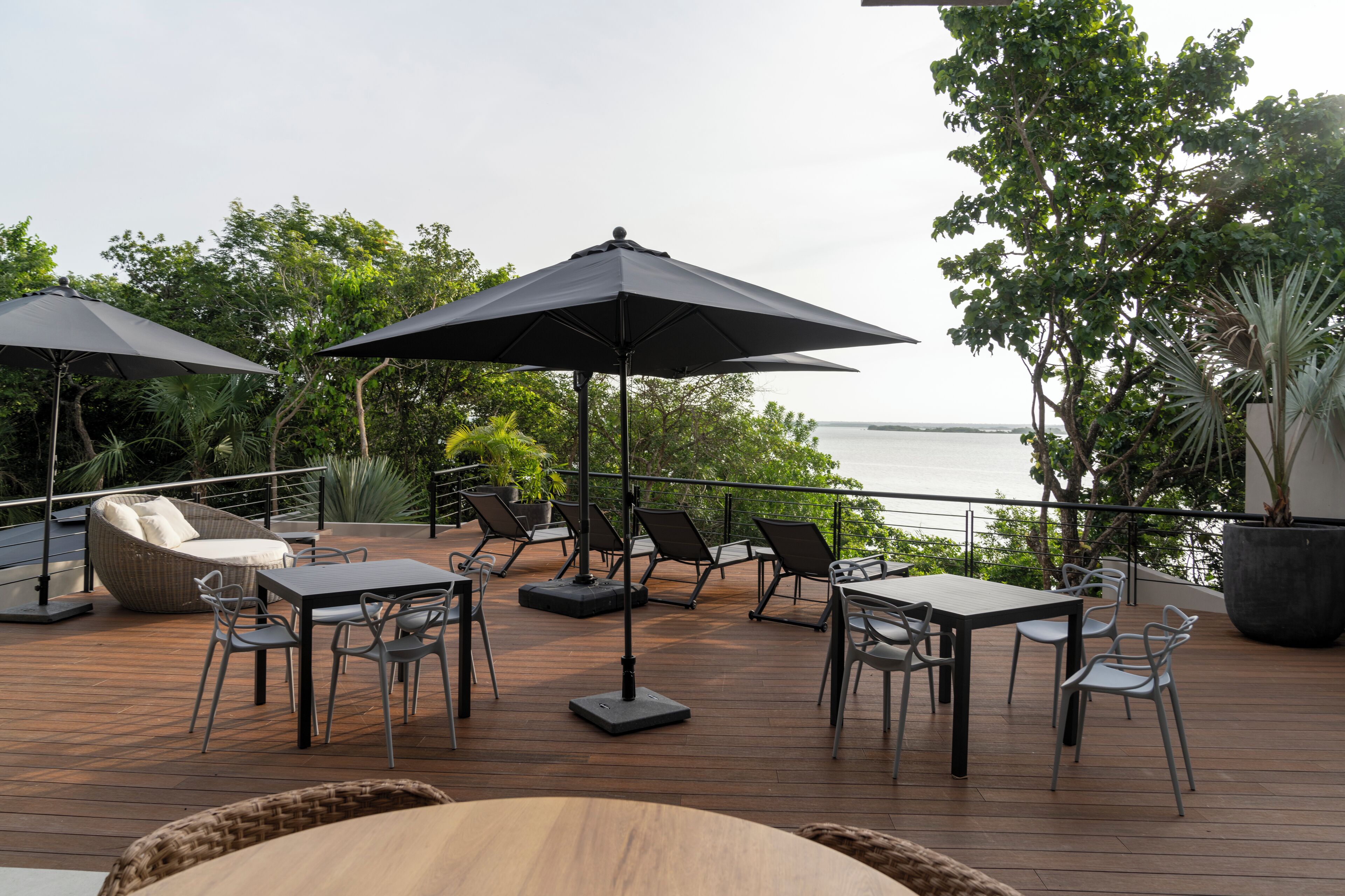 An outdoor deck with tables and chairs, umbrellas, and a view of the water.