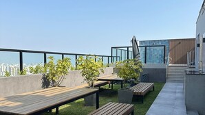 Une terrasse sur le toit, avec des bancs en bois, des plantes en pot et un chemin en béton.