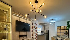 Un salon moderne avec un canapé, un téléviseur et des luminaires suspendus.