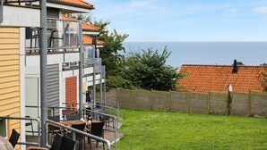 A building with a balcony overlooking a grassy area and the sea.