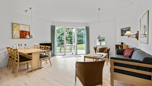 A modern living room with a wooden dining table, a sofa, and a TV.