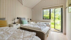 A bedroom with two beds, a window with a view of greenery, and a sliding glass door. - 4 bedroom awesome home in Hornbæk (Hornbæk)