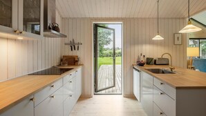 A modern kitchen with wooden cabinets, a central island, and a view of the outdoors. - 4 bedroom awesome home in Hornbæk (Hornbæk)