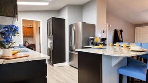 A modern kitchen with a central island, dark cabinetry, stainless steel appliances, and a breakfast setup. - Big house w custom murals/2 Kings/Fun backyard w Games/Grill/Dog OK/Boat parking (Page)