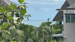 A view of a coastal property with lush greenery and a clear view of the ocean. - Villa Amici (Canggu)