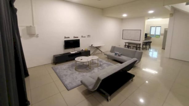 Uma sala de estar moderna com um sofá cinzento, uma mesa de centro, uma televisão e um ventilador de teto.