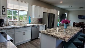 A modern kitchen with white cabinets, a granite countertop, and a built-in dishwasher. - Completely Remodeled and Modernized Smart Home in Payson (Payson)