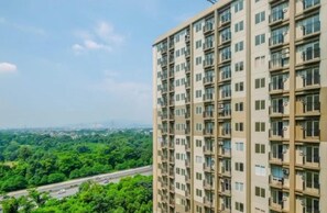 Un edificio residencial alto con varios balcones y vistas a una autopista y áreas verdes.