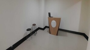 Un rincón de una habitación con un atril de madera, un taburete pequeño y una silla de metal.