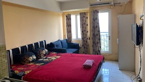 Un dormitorio con cama, sofá, televisor y armario.