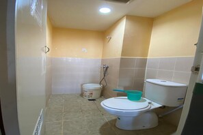 Un baño pequeño con inodoro, ducha y un balde.