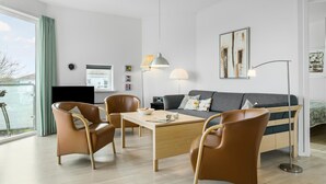 A modern living room with a sofa, two chairs, a table, and a TV. - Gudhjem Søpark Lejl. 26 (Gudhjem)
