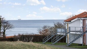 A coastal building with a staircase leading to a balcony overlooking the sea. - Gudhjem Søpark Lejl. 26 (Gudhjem)
