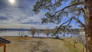 A lakeside property with a fenced area, a wooden deck, and a view of the water. - Lakefront, Fireplace, Large Deck, Yard & Dock. Mins from Uptown Dining & Trails! (Pagosa Springs)