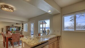A modern kitchen with a granite countertop, stainless steel appliances, and a dining area with a wooden table and chairs. - Lakefront, Fireplace, Large Deck, Yard & Dock. Mins from Uptown Dining & Trails! (Pagosa Springs)