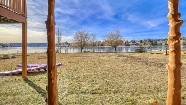 A wooden deck with a view of a lake and trees. - Lakefront, Fireplace, Large Deck, Yard & Dock. Mins from Uptown Dining & Trails! (Pagosa Springs)