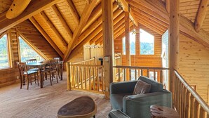 Eine geräumige Holzhütte mit hoher Decke und einer Essecke mit Holztischen und -stühlen.
