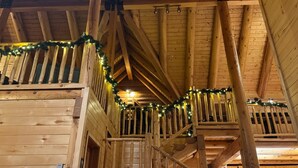 Ein Holzinnenraum mit Treppe, Holzbalken und einer mit Lichterketten verzierten Geländer.
