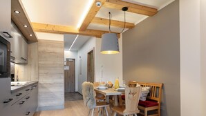 A modern kitchen with wooden beams, a dining area with a wooden table and chairs, and a visible door leading to another room. - Beautiful apartment with a sauna and a balcony (Haus im Ennstal)