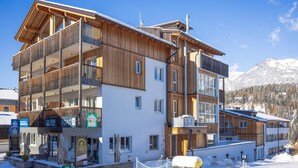 A multi-story hotel with wooden exterior and balconies, situated in a snowy mountainous area. - Beautiful apartment with a sauna and a balcony (Haus im Ennstal)