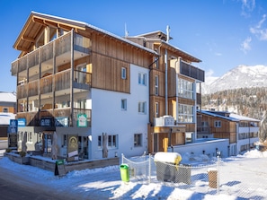 Un hotel de varios pisos con fachada de madera y balcones, ubicado en una zona montañosa nevada.