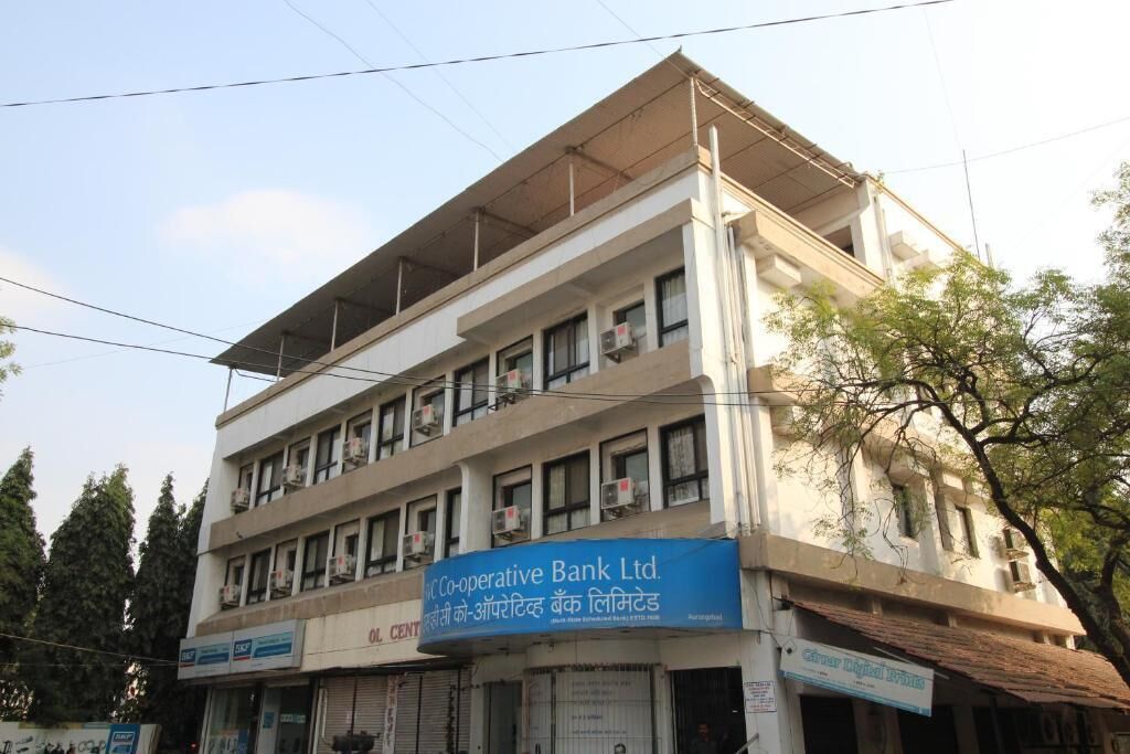 Un immeuble à plusieurs étages, sur lequel on peut voir des enseignes indiquant la présence de la banque IC Co-operative Bank Ltd., et un magasin fermé appelé Old Center.