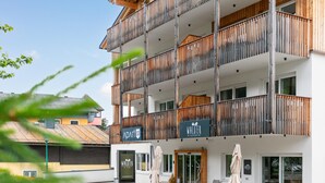 A multi-story building with balconies, a sign for 'WALTER PIZZERIA', and outdoor seating. - Atmospheric with a sunny balcony and summercard (Haus im Ennstal)