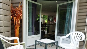 A patio area with two white plastic chairs, a small table, and a decorative plant. - Le Petit Jules (Agen)