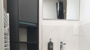 A bathroom with a black wardrobe, white vanity, and a mirror above the sink. - Le Petit Jules (Agen)
