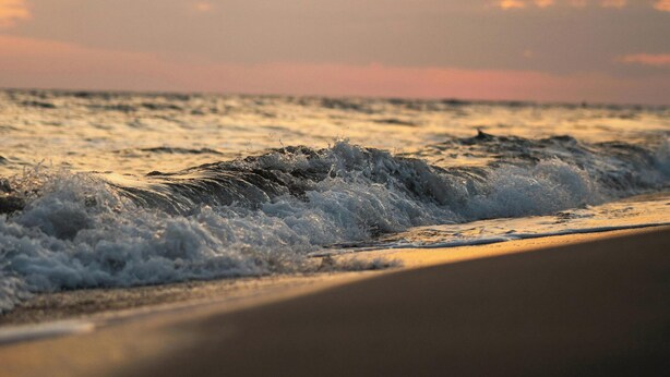 Una playa con olas y un atardecer.