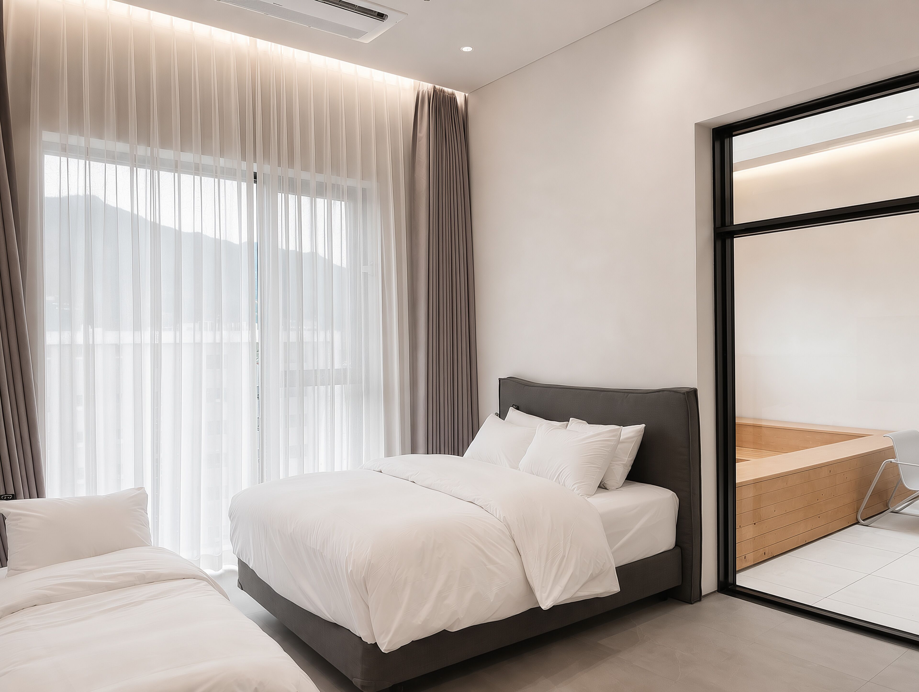 Un dormitorio moderno con cama, cortinas y un ventanal grande.