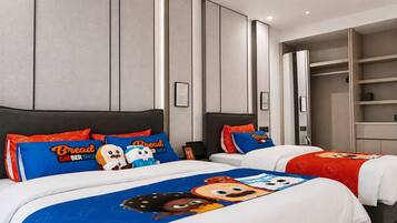Habitación de hotel con dos camas, cada una con ropa de cama y almohadas temáticas, un armario y una mesita de noche.