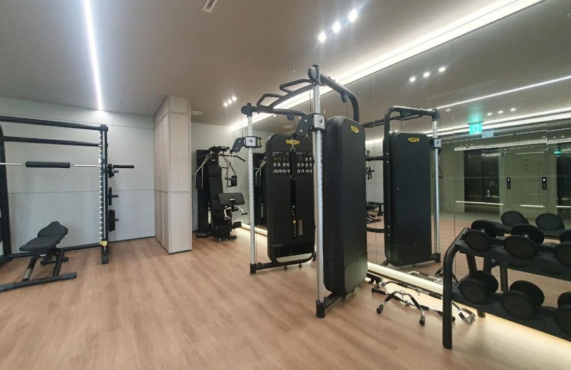 A gym with various exercise equipment, including a squat rack, weight bench, and dumbbells.