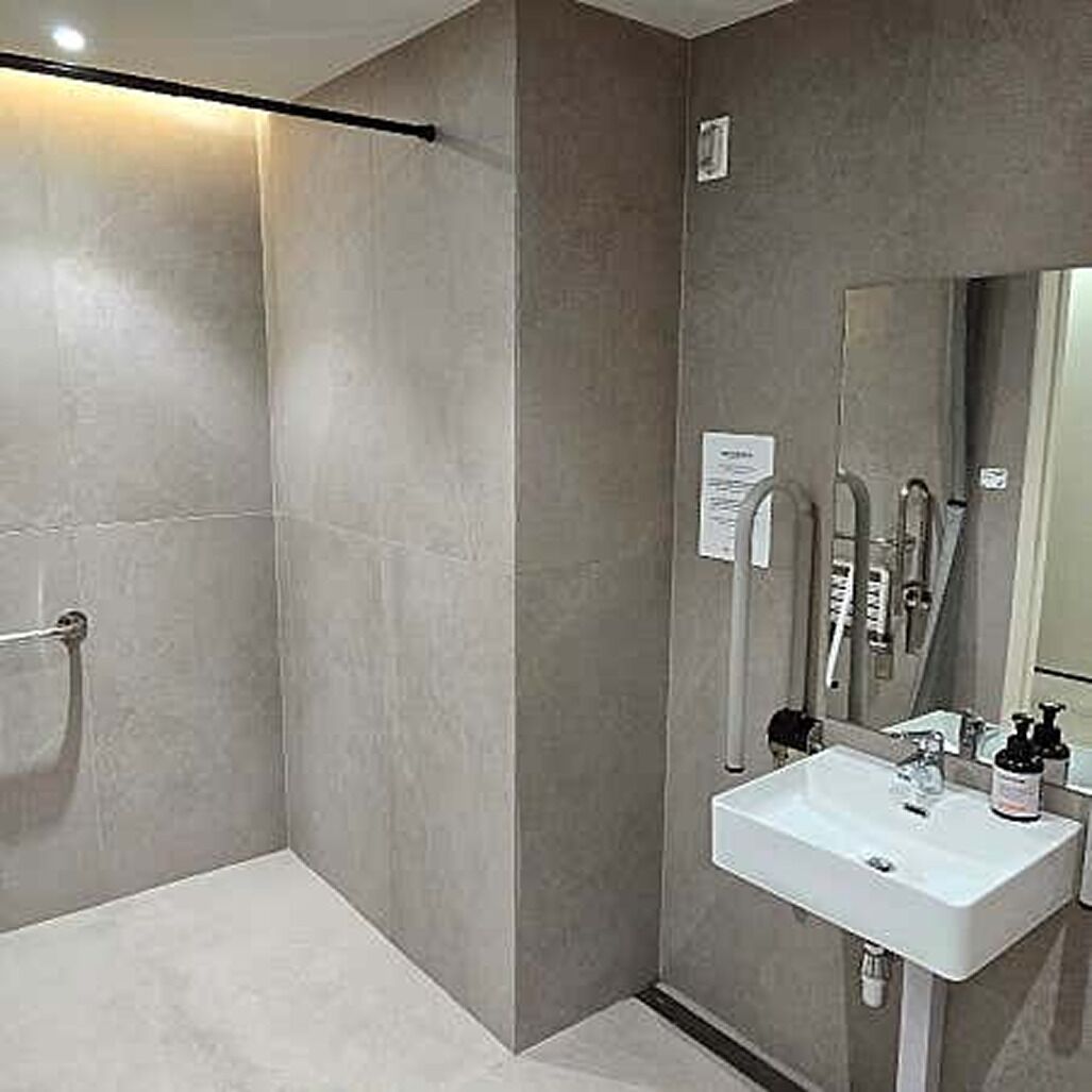 Un baño moderno con ducha, lavabo y espejo.