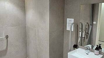 Un baño moderno con ducha, lavabo y espejo.