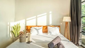 A hotel room with a bed, a potted plant, a woven basket, and a lamp. - Lane House 2 (Canggu)