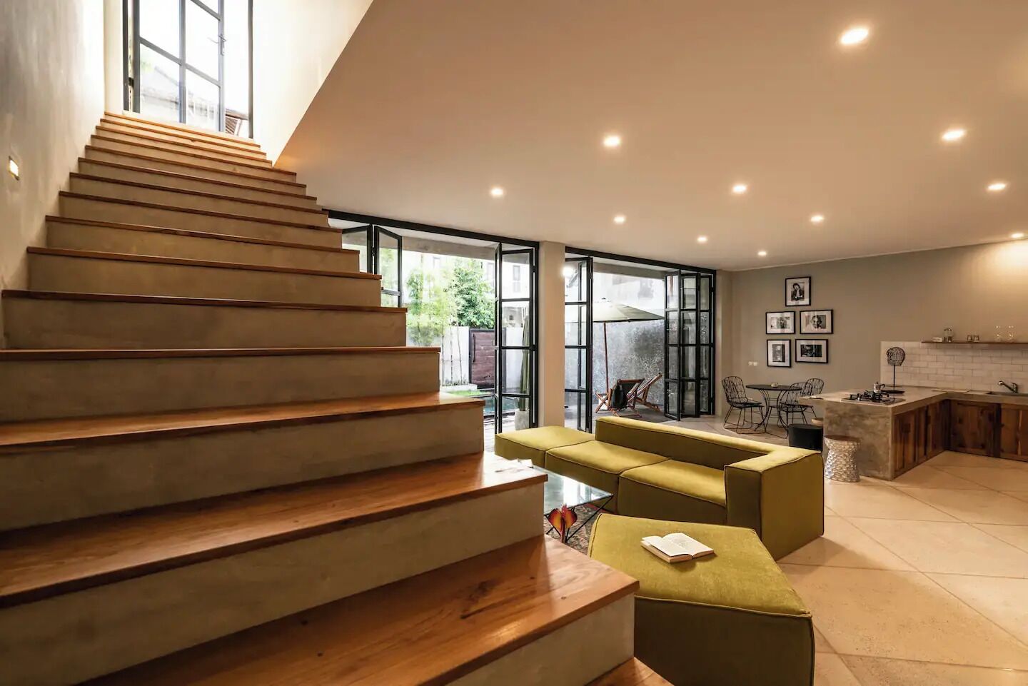 Un interior moderno con una escalera de madera, un sofá amarillo y una zona de cocina.