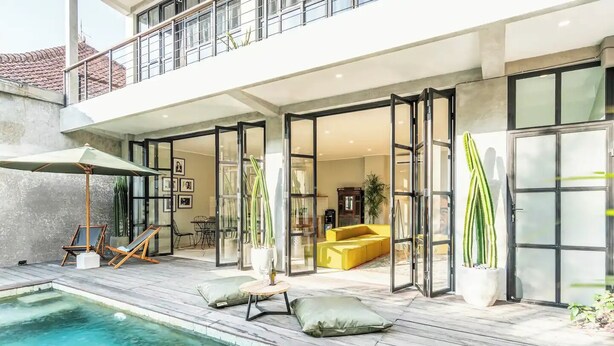 A modern house with a pool, a yellow sofa, and a dining area. - Lane House 2 (Canggu)