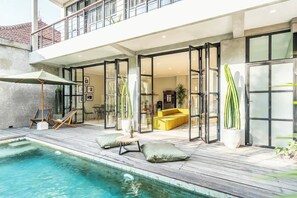 A modern house with a pool, a yellow sofa, and a dining area. - Lane House 2 (Canggu)