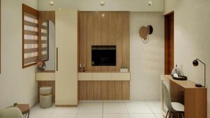A modern, well-lit room with a built-in TV, wooden panel wall, and a small desk with a chair. - Q-ONE by Glitz hotels (Kanayannur)