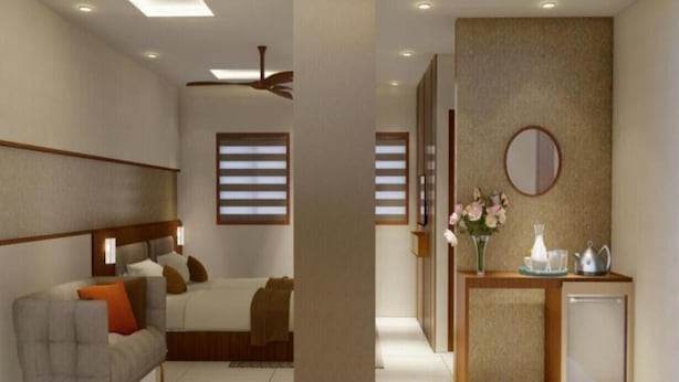 A modern hotel room with a bed, a sofa, a small table, and a mirror. - Q-ONE by Glitz hotels (Kanayannur)