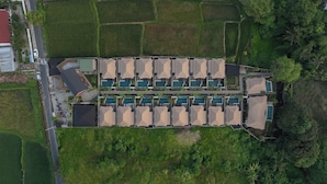 An aerial view of a resort with multiple swimming pools arranged in rows, surrounded by lush greenery and a few buildings. - Ubud Mas Glamping Luxury Tent (Mas)