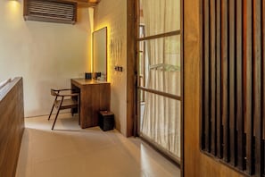 Un couloir avec un bureau en bois, une chaise et un miroir.